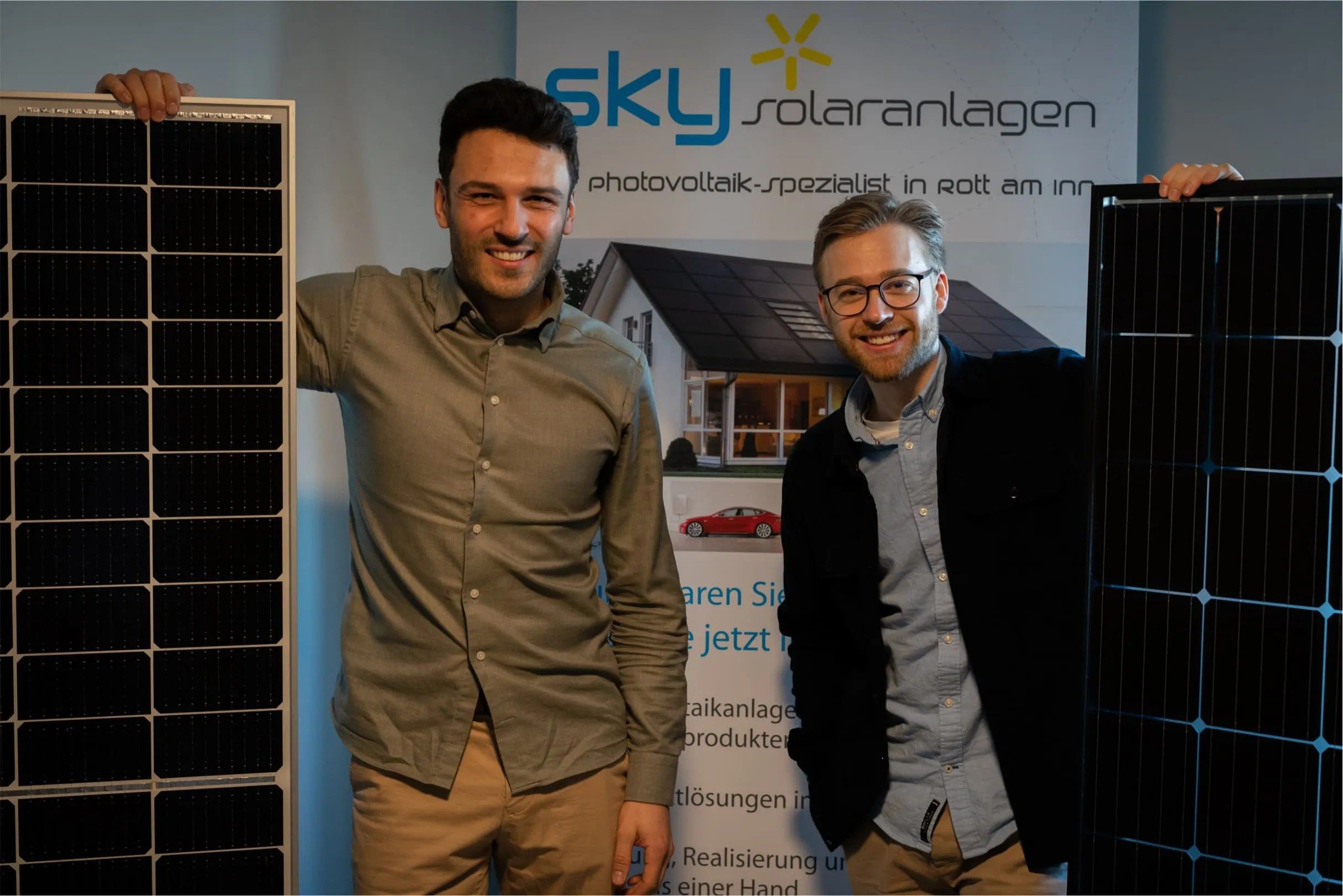 Paul Kahle und Steven Heisig halten je ein Solarmodul vor einem Sky-Solar-Banner